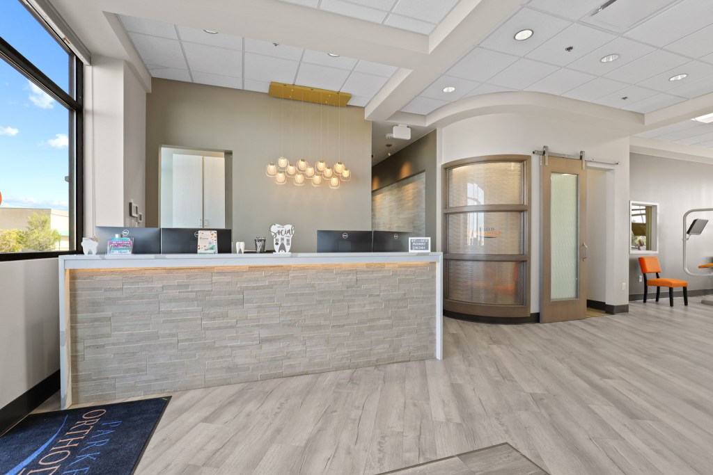 Modern dental office reception area with a sleek front desk, stylish lighting, and welcoming decor.