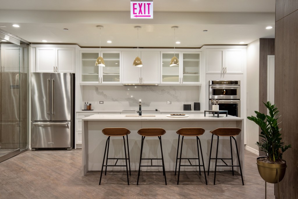 Modern kitchen interior featuring stainless steel appliances, a large island with bar stools, and stylish lighting fixtures.