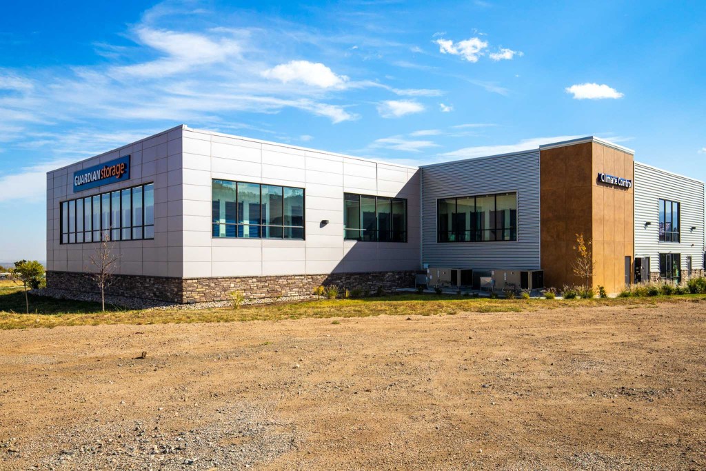 Exterior view of a modern storage facility building featuring large windows and signs indicating 'GUARDIAN storage' and 'climate control'.