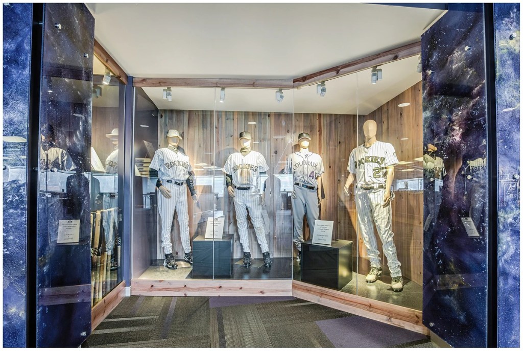 Display case featuring mannequins dressed in Colorado Rockies baseball uniforms at Coors Field.