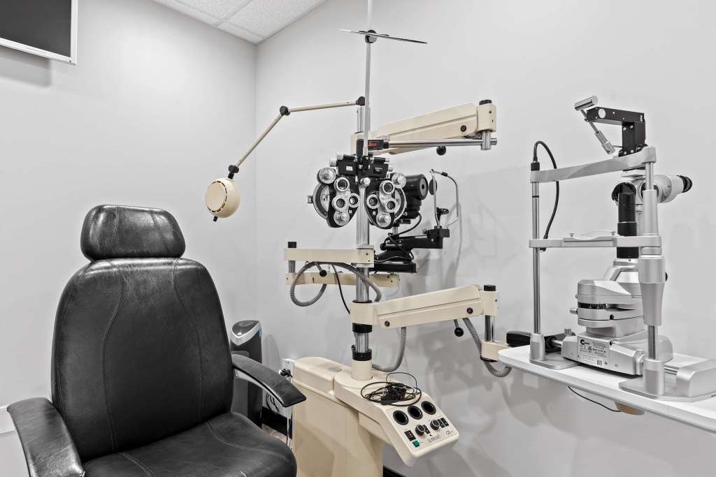 Interior view of an eye examination room featuring an examination chair, various ophthalmic equipment, and a clean, organized space.