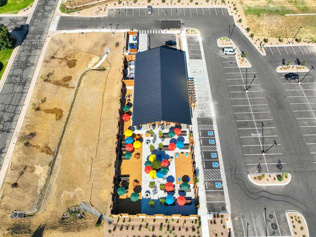 Aerial view of Billy Birch Pub and Yard showcasing colorful umbrellas on the outdoor patio, surrounded by a parking area and landscaped grounds.