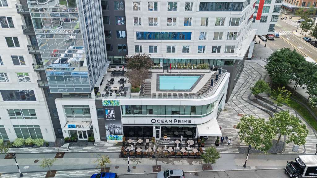Aerial view of the 100 Pier 4 luxury apartments in Boston, featuring a rooftop pool and outdoor seating area.
