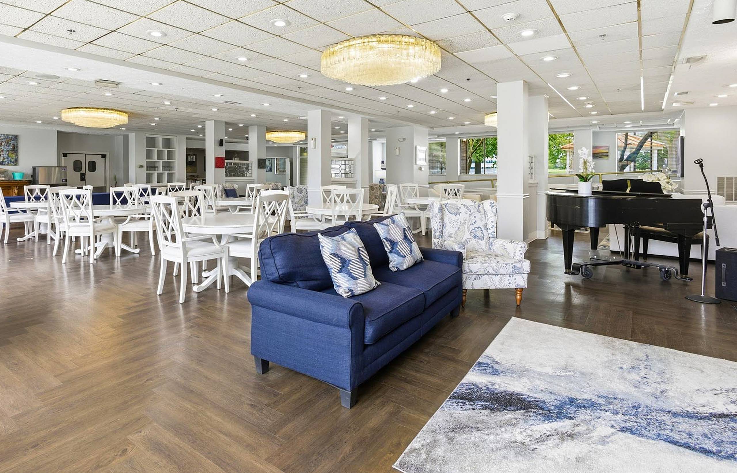 Chandelier-lit dining and activity hall with a grand piano at King’s Reserve College Park
