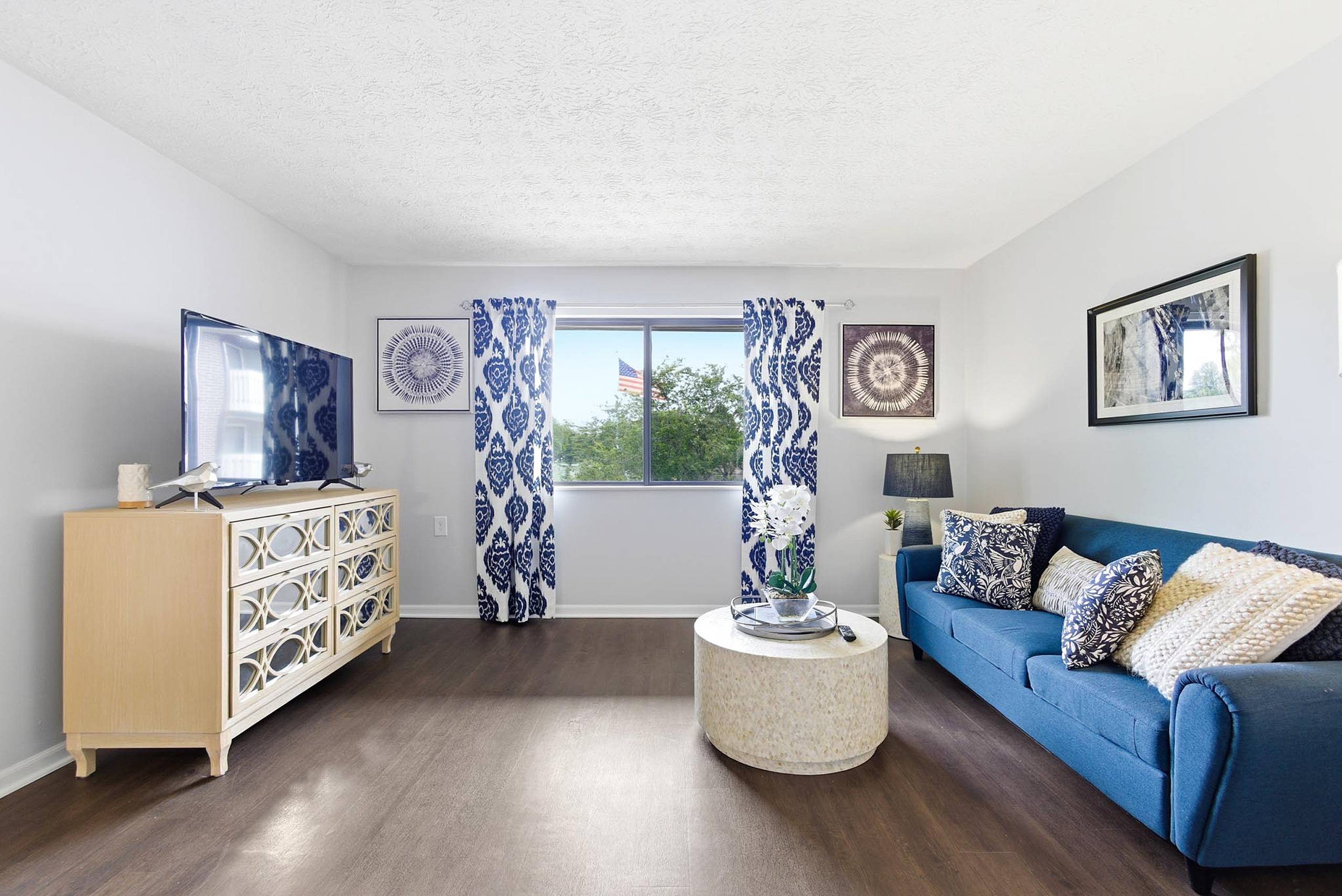 Furnished model apartment living room with blue sofa at King’s Reserve College Park