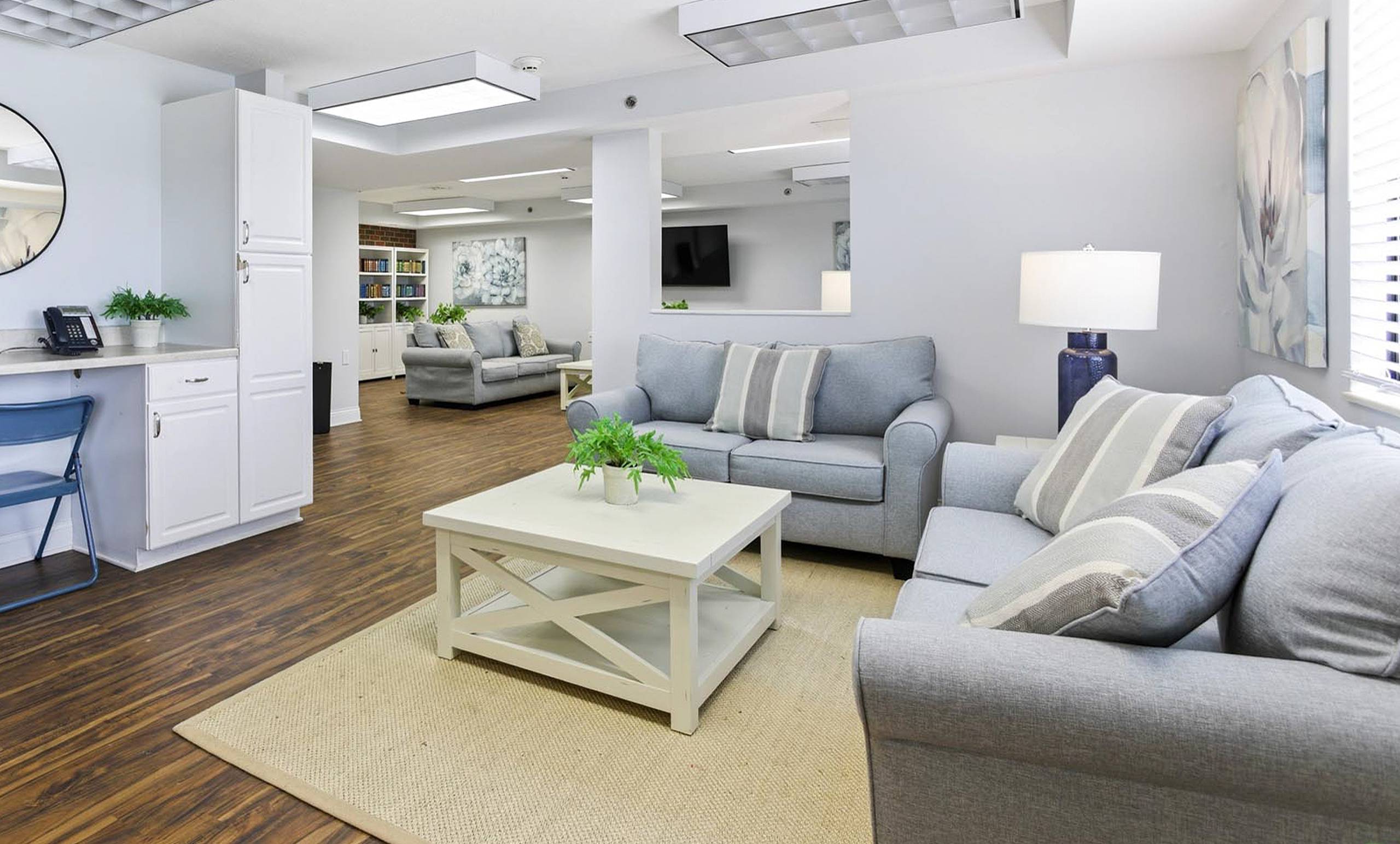 Resident lounge with gray sofas, computer desk and library nook at King's Reserve College Park