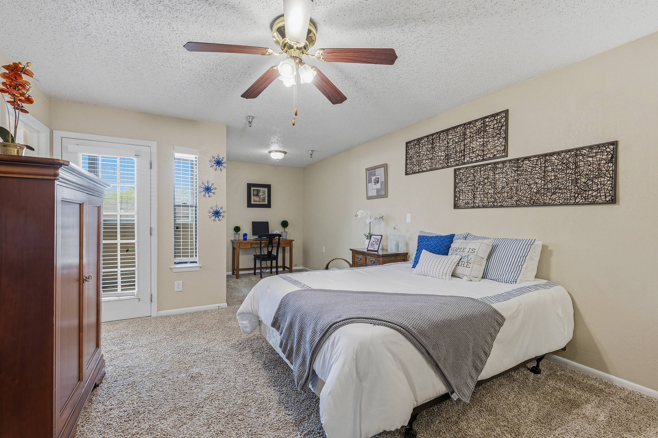 Spacious model primary bedroom with desk nook and patio door at Serenity at Briarcrest