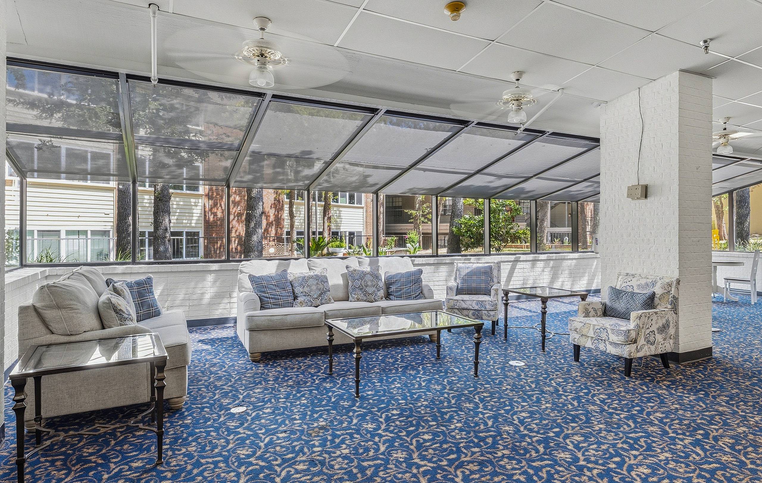 Glass sunroom lounge with sofas overlooking the courtyard at Serenity at Briarcrest