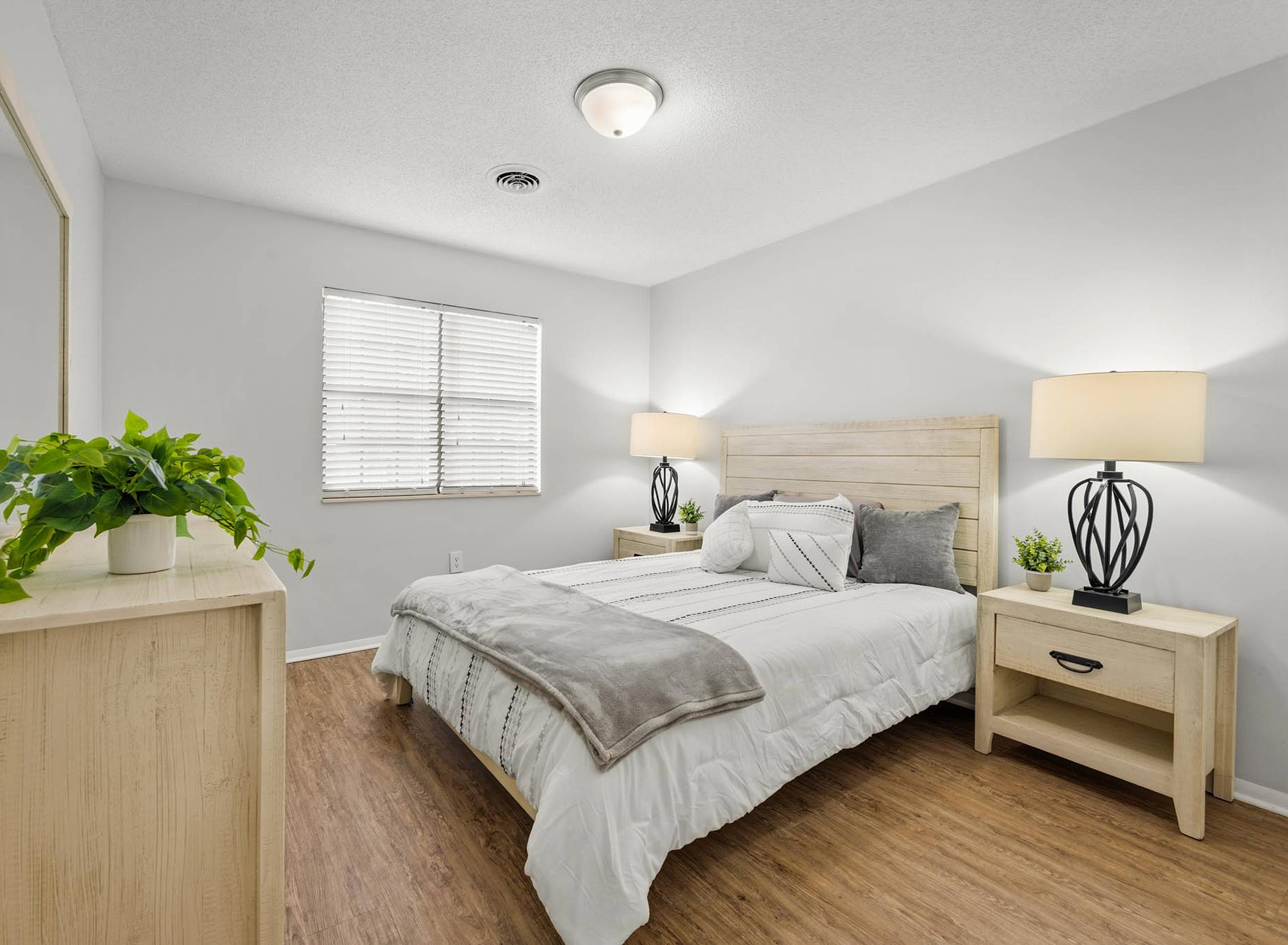 Furnished model bedroom with wood plank headboard and vinyl plank floors at Serenity at Easley in Easley, South Carolina