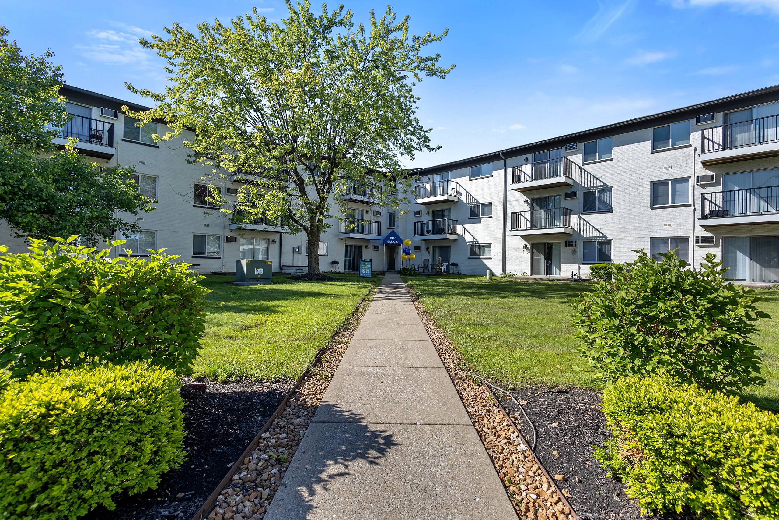 Landscaped courtyard walkway between three-story apartment buildings at Serenity Manor at Indianapolis