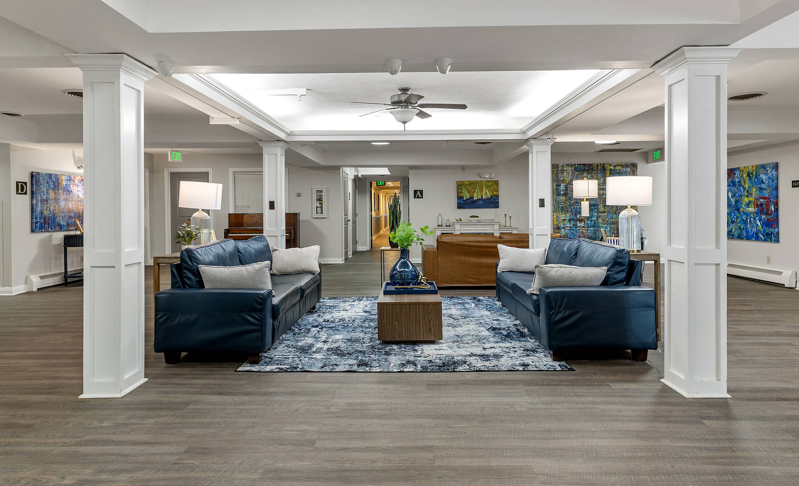 Main lobby lounge with navy leather sofas and a piano at Serenity Manor at Indianapolis